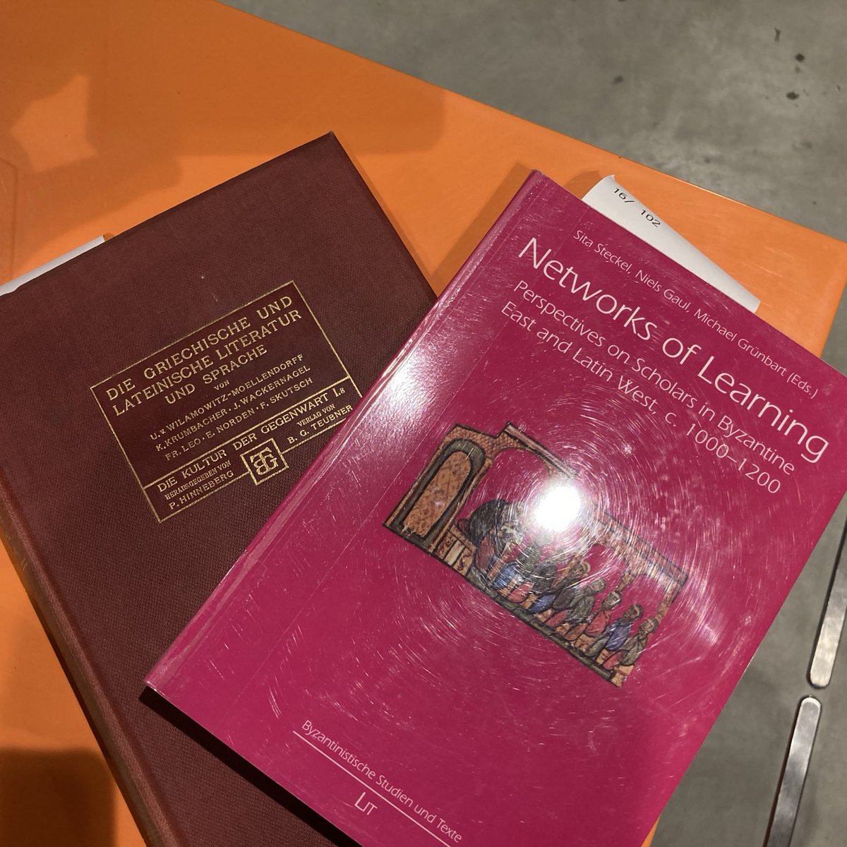 To fjernlånsbøker på et oransje bord på biblioteket: Die griechische und lateinische Literatur und Sprache, og Networks of Learning om lærde i Bysants og Vesten